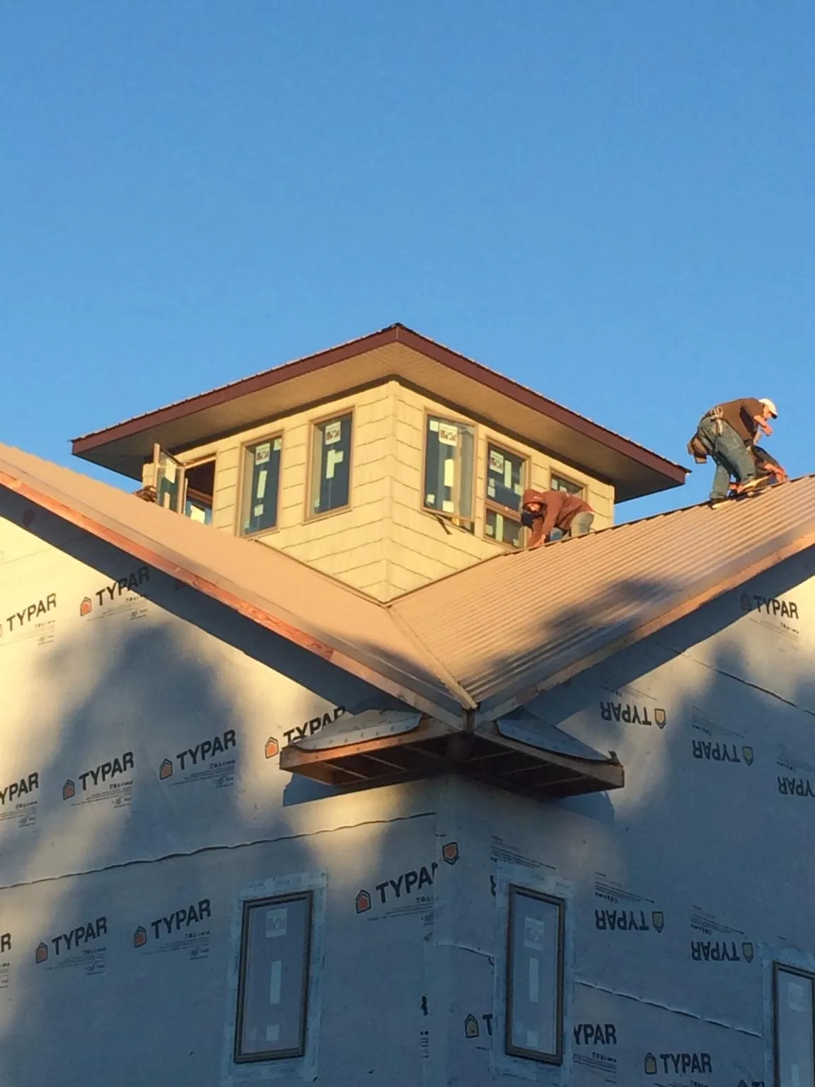 Roofers working around a rooftop cupola on a new metal roof at sunset — Roof Waterproofing in Leesburg by Roofing Brothers